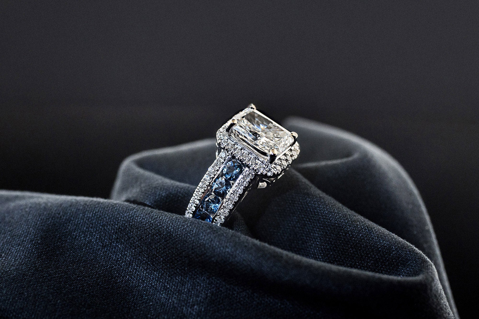 Side view of sapphire channel band on diamond halo engagement ring