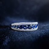 Graduated round blue sapphire band between two rows of pavé diamonds in 14K white gold