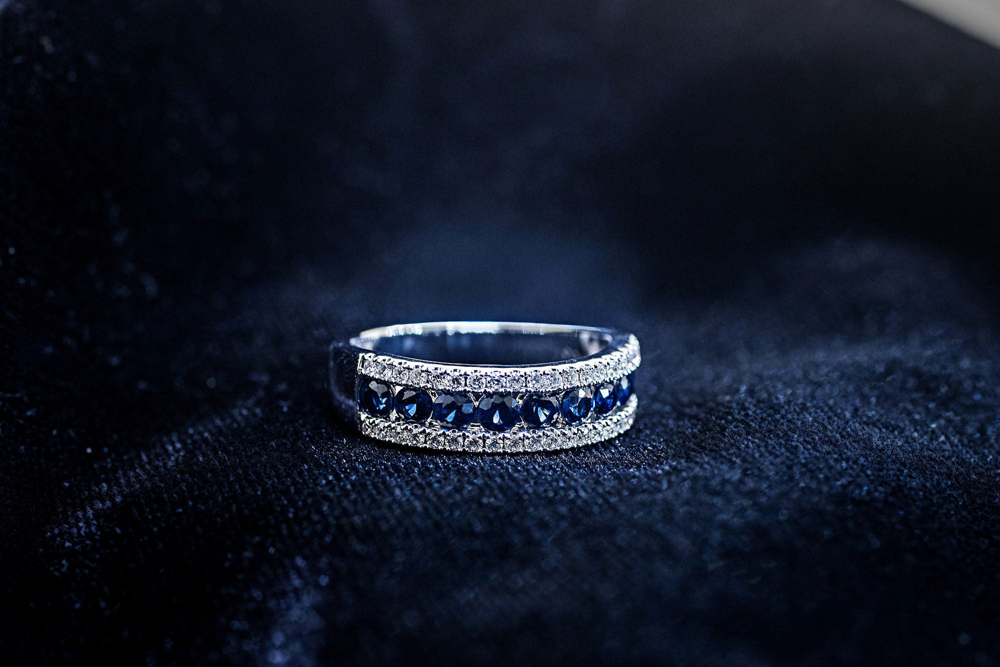 Round blue sapphire band between two rows of pavé diamonds in 14K white gold